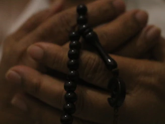 a close up of a person holding a rosary