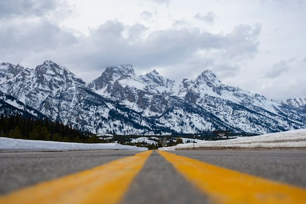 A road with a yellow line in front of a mountain range — Grand Teton, United States