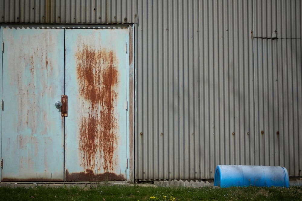 a rusted door and a trash can in front of a building