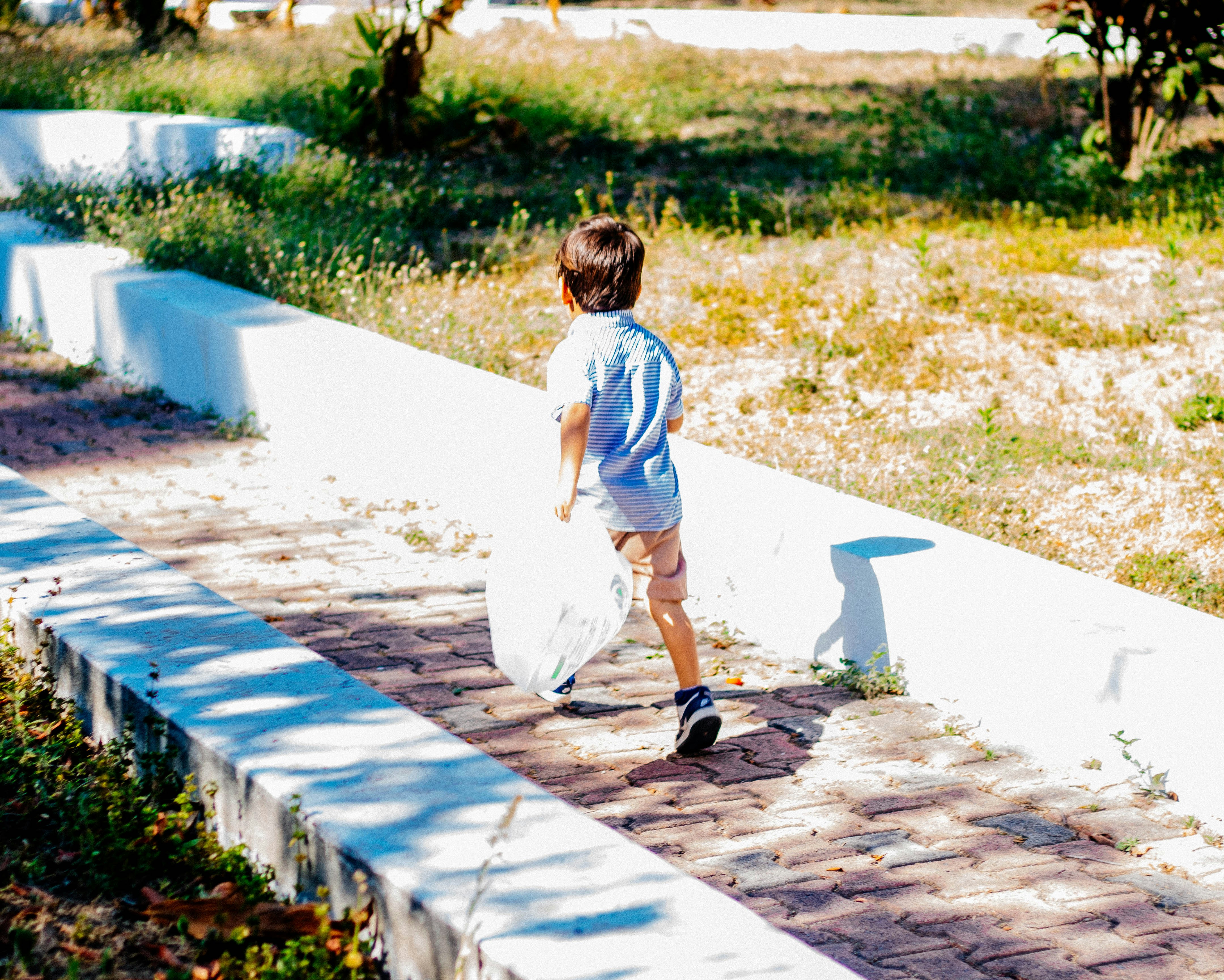 a little boy that is walking down a sidewalk
