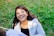 a woman sitting in the grass with a smile on her face