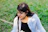 a woman sitting in the grass with a cell phone