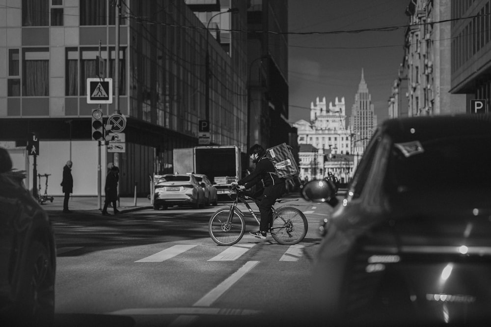 a man riding a bike down a street next to tall buildings