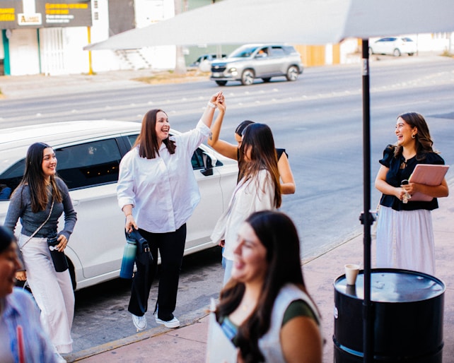 a group of women standing next to a white car