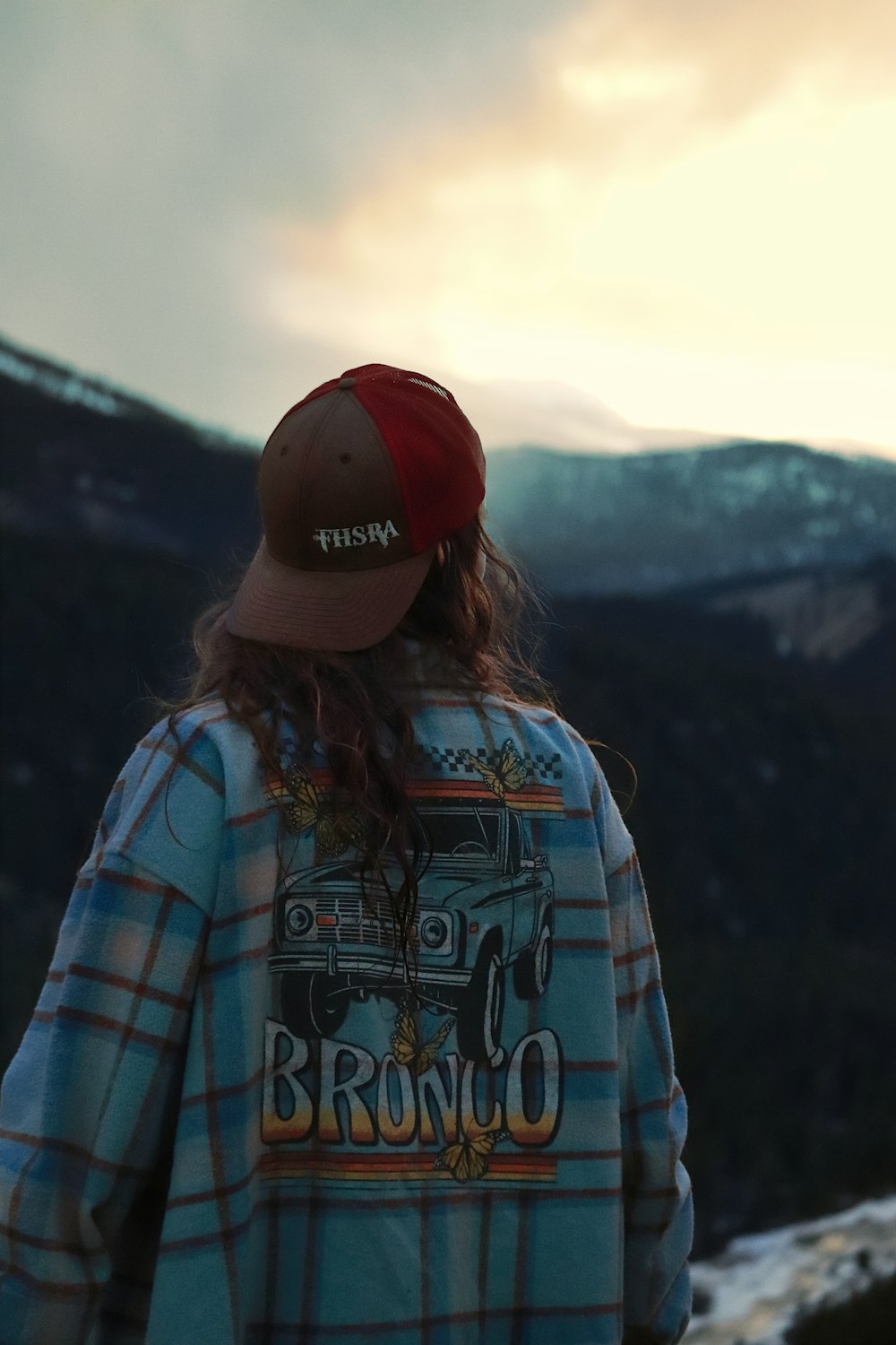 una persona con un sombrero de pie frente a una montaña