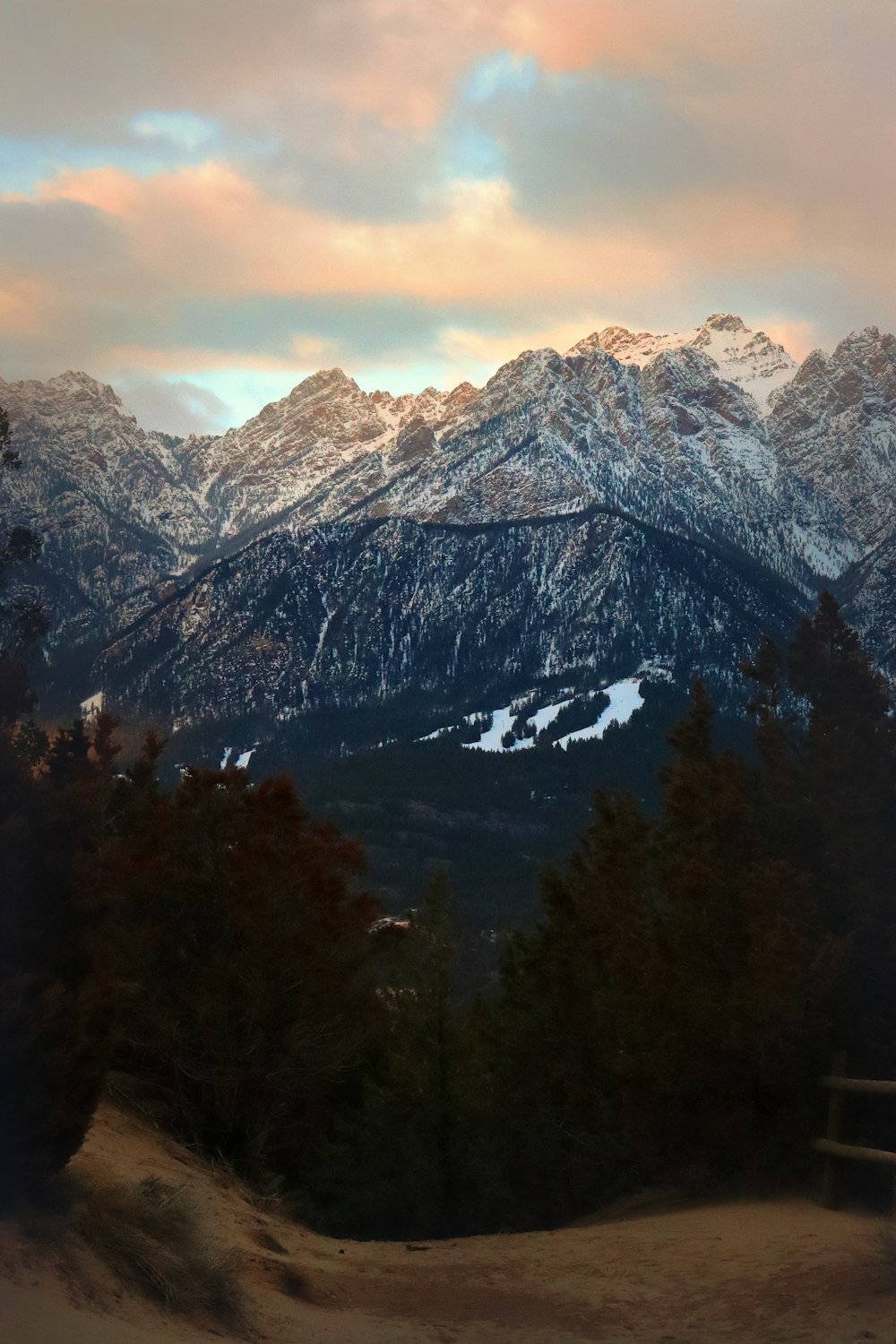 Una vista de una cadena montañosa con un banco en primer plano