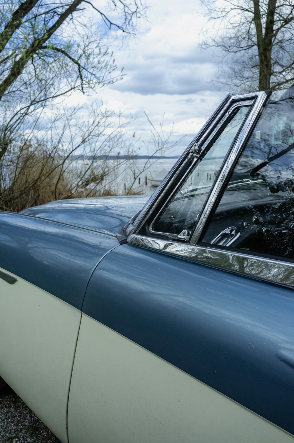 a blue and white car parked next to a body of water