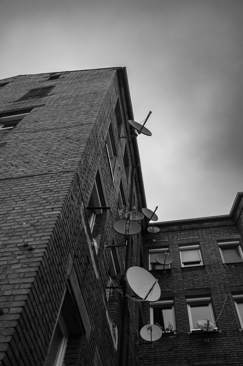 a black and white photo of a satellite dish on the side of a building