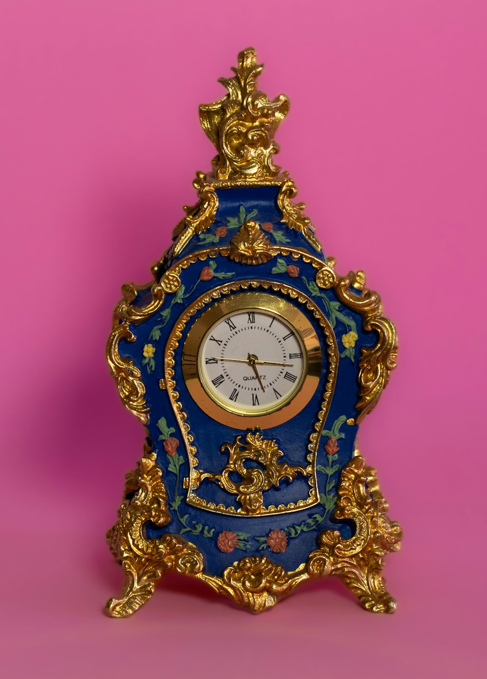a blue and gold clock on a pink background