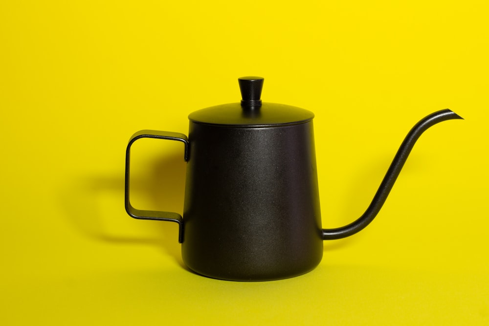 a black coffee pot on a yellow background