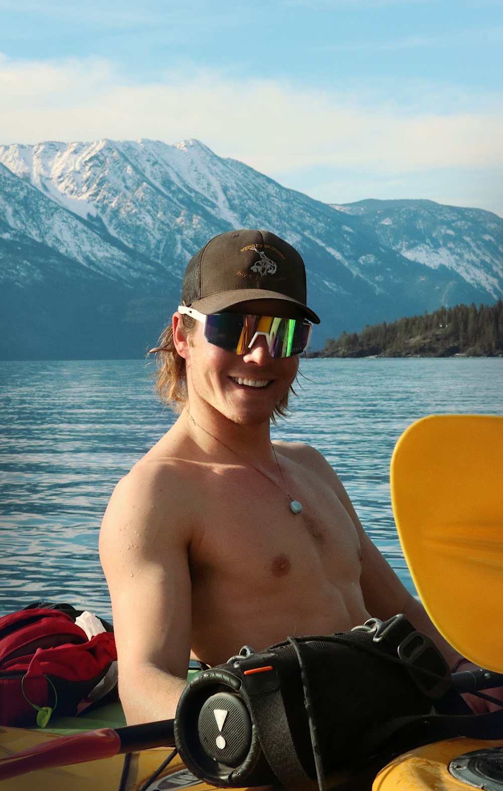 a shirtless man sitting in a kayak on a lake