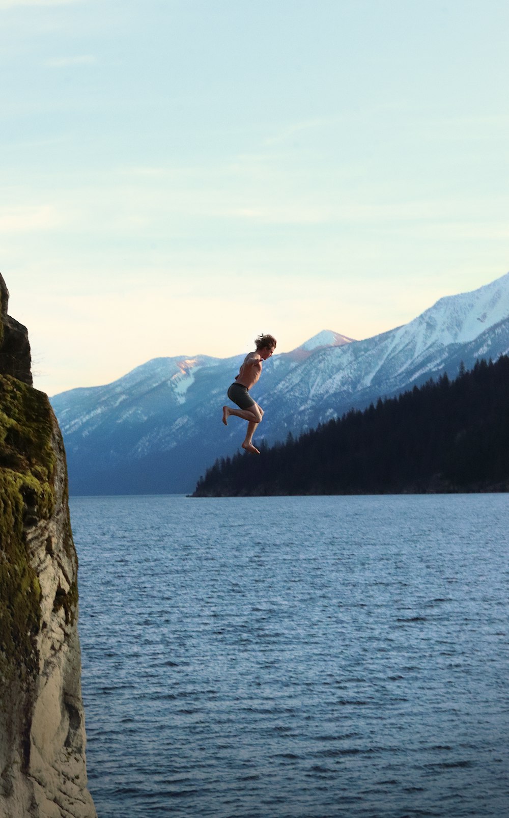 a man jumping off a cliff into a lake