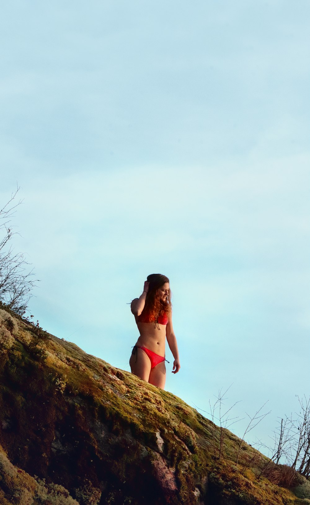 a woman in a bikini standing on top of a hill