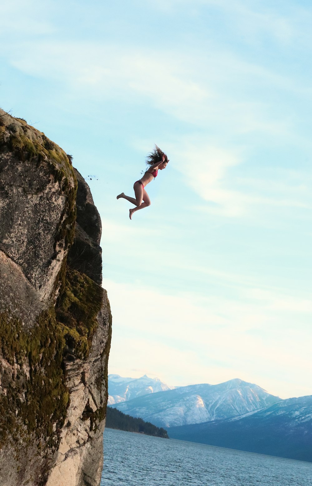 a woman jumping off a cliff into the water