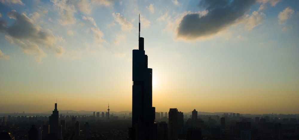 the sun is setting behind a tall skyscraper