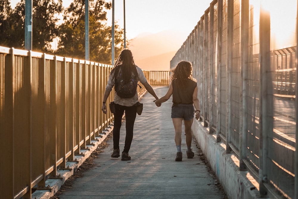 two people walking down a bridge holding hands