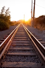 a train track with the sun setting behind it