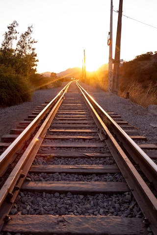 a train track with the sun setting behind it