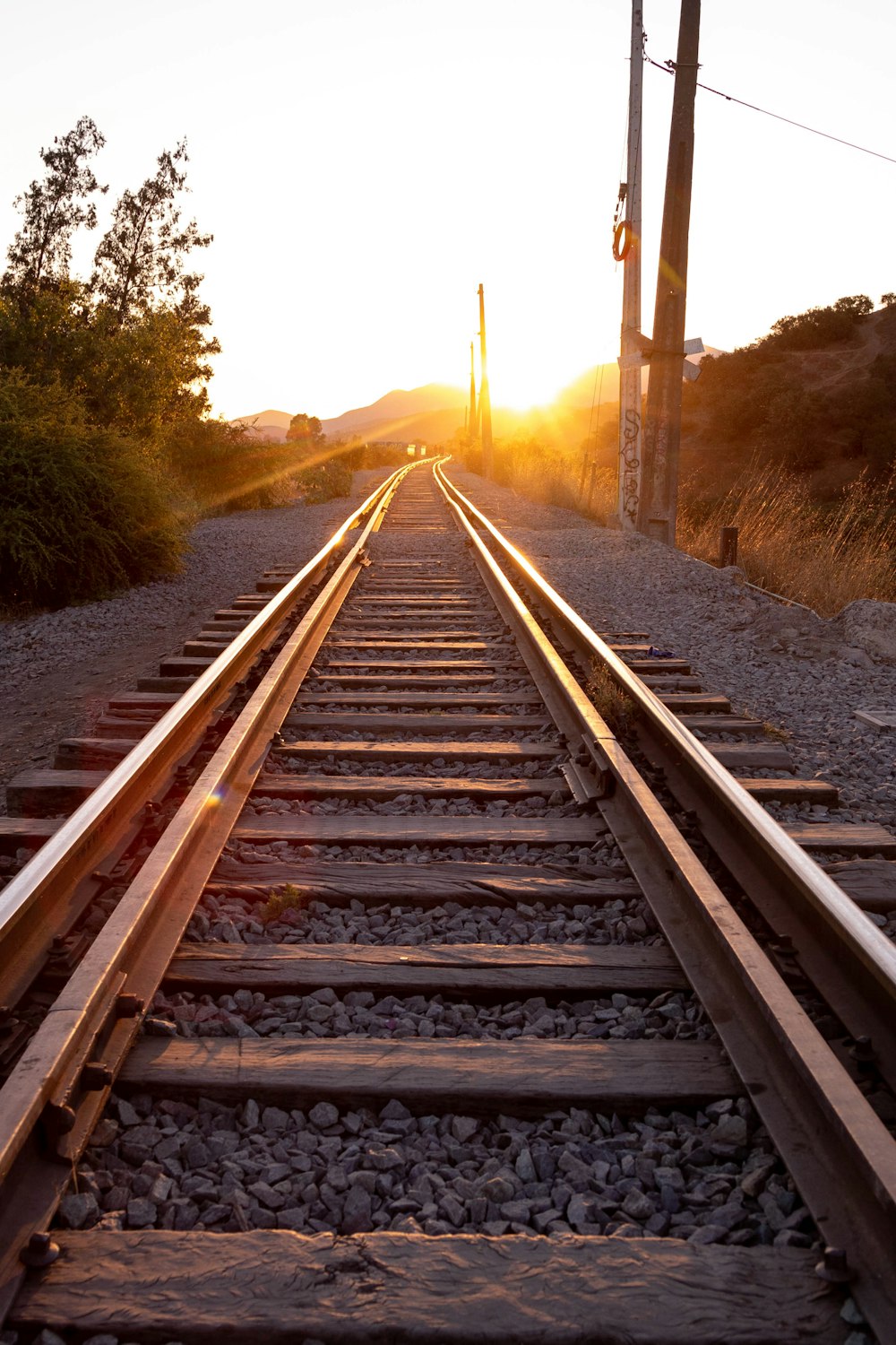 a train track with the sun setting behind it