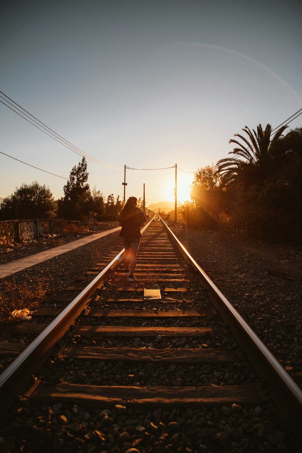 a person standing on a train track at sunset