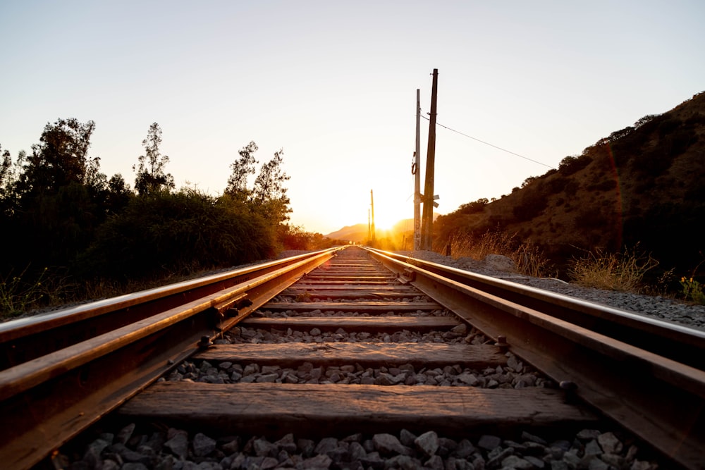 a train track with the sun setting in the background
