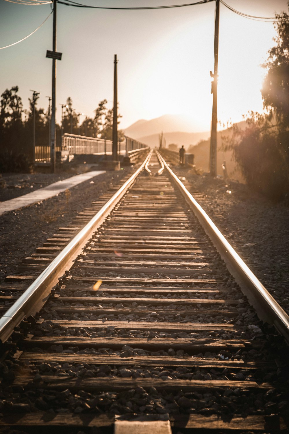 a train track with the sun setting in the background