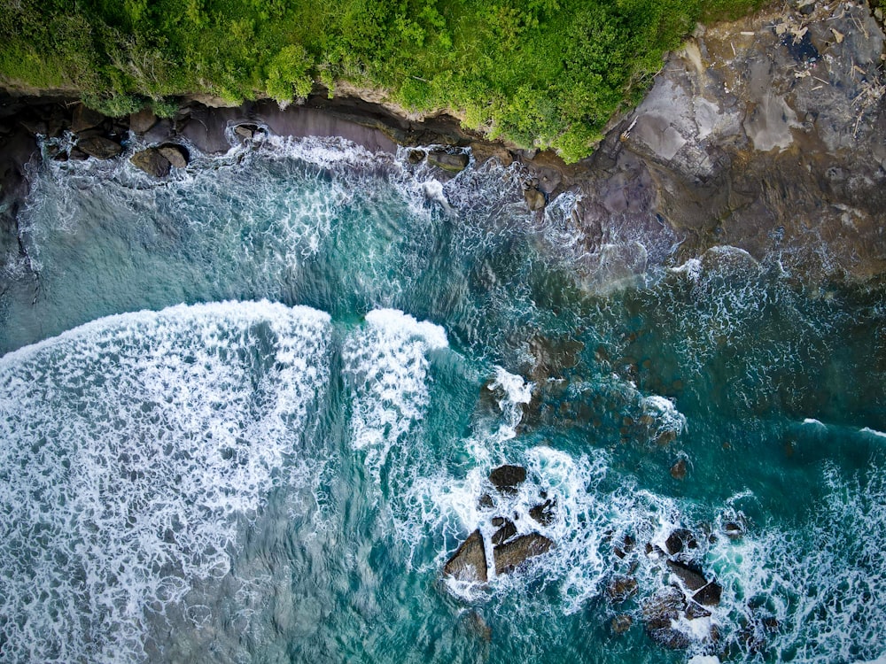 an aerial view of a body of water next to a lush green hillside