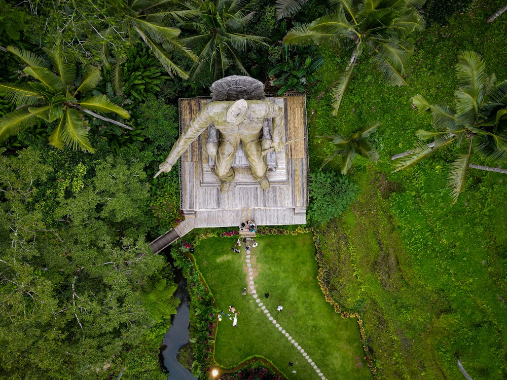 an aerial view of a statue in the middle of a forest