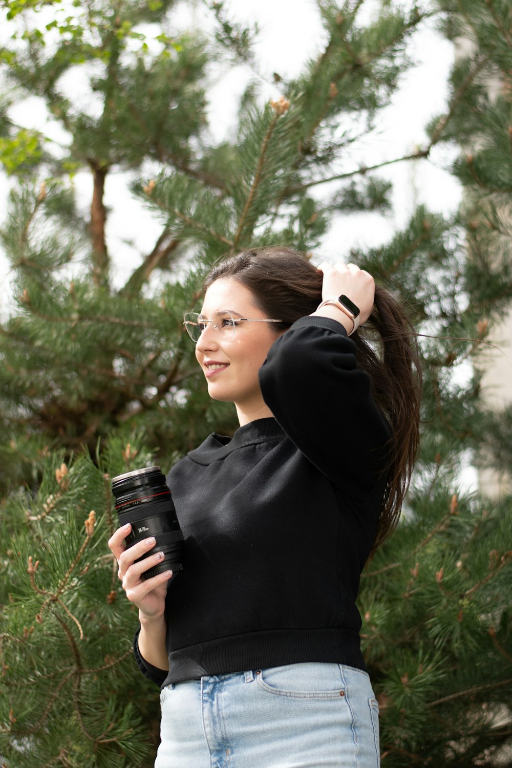 a woman in a black top is holding a cell phone