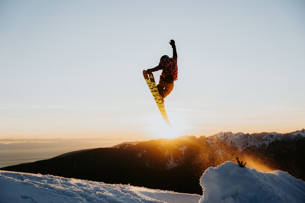 a man flying through the air while riding a snowboard