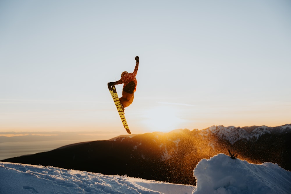 a man flying through the air while riding a snowboard