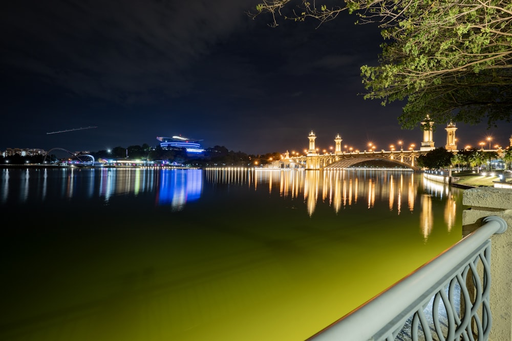 a night view of a lake with a bridge in the background