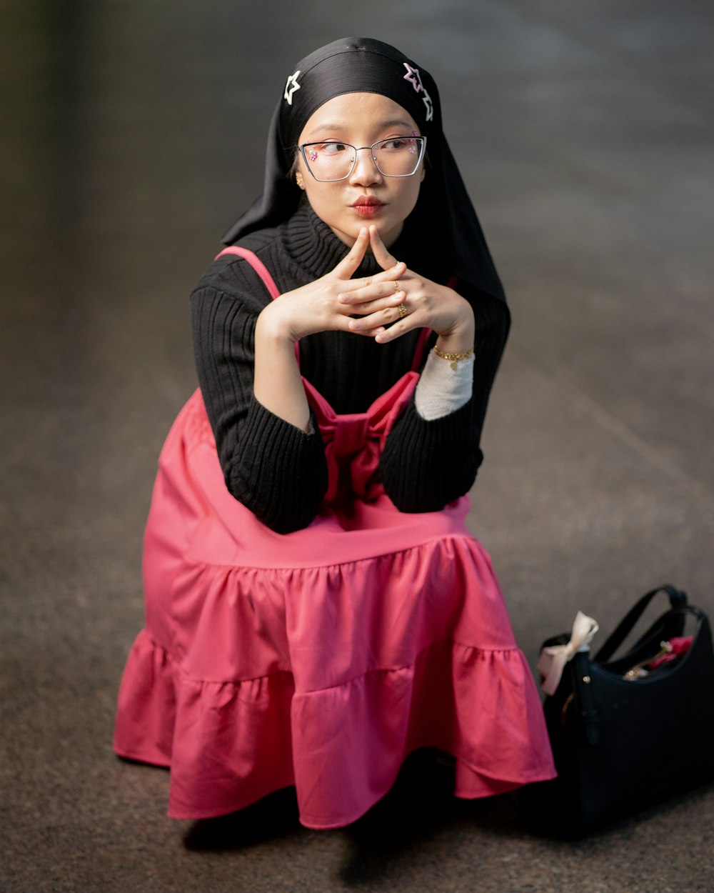 a woman sitting on the ground with her hand on her chin