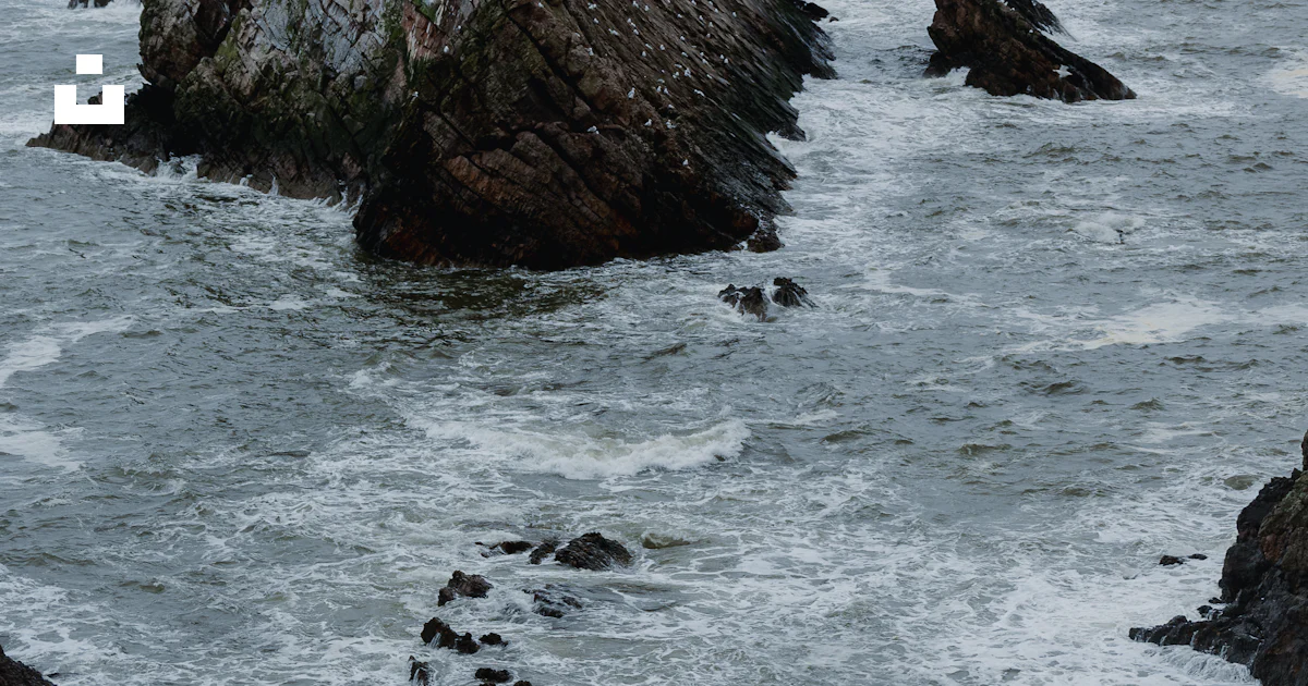 A large rock sticking out of the ocean photo – Free Nature Image on ...