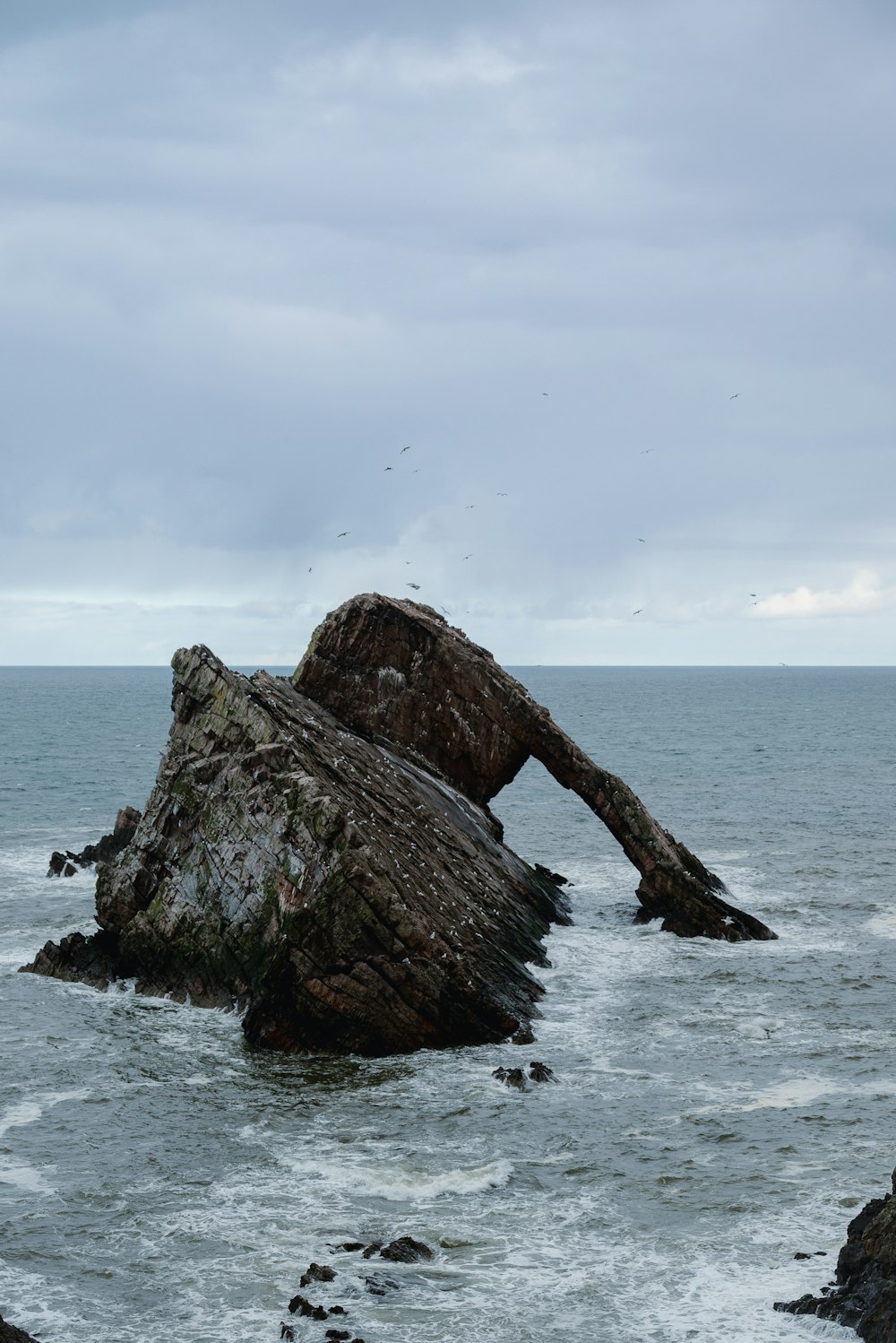 a large rock sticking out of the ocean