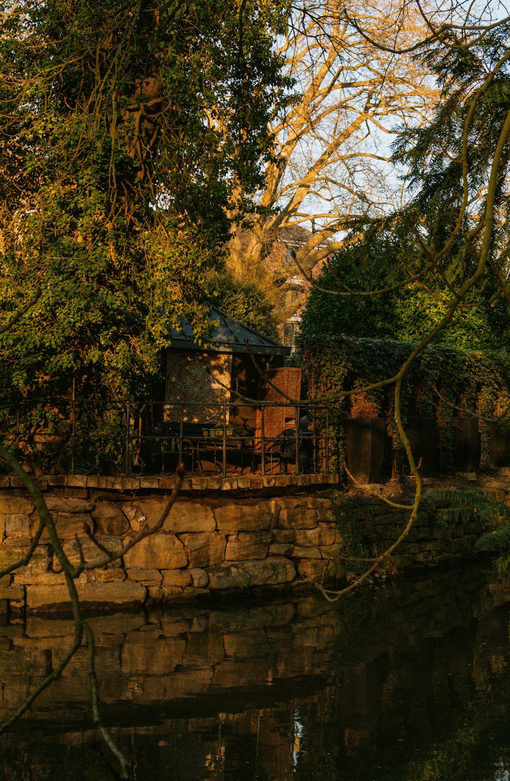 a house sitting on the side of a river next to a forest