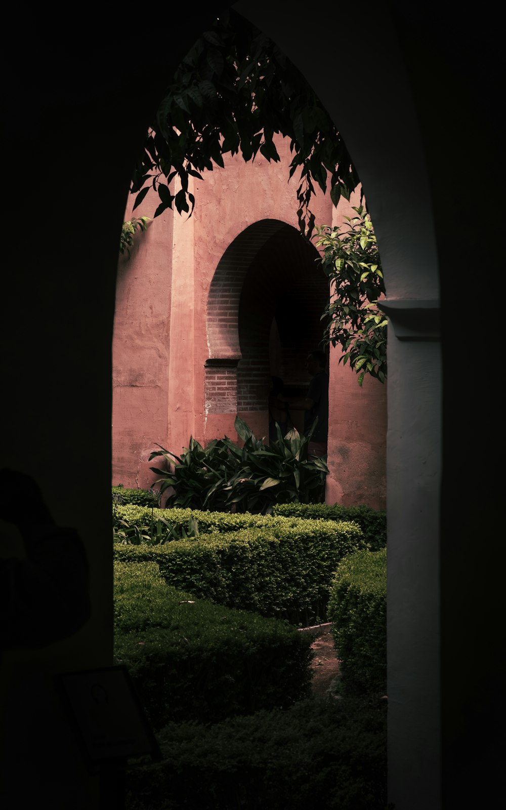 uma vista de um jardim através de um arco em um edifício