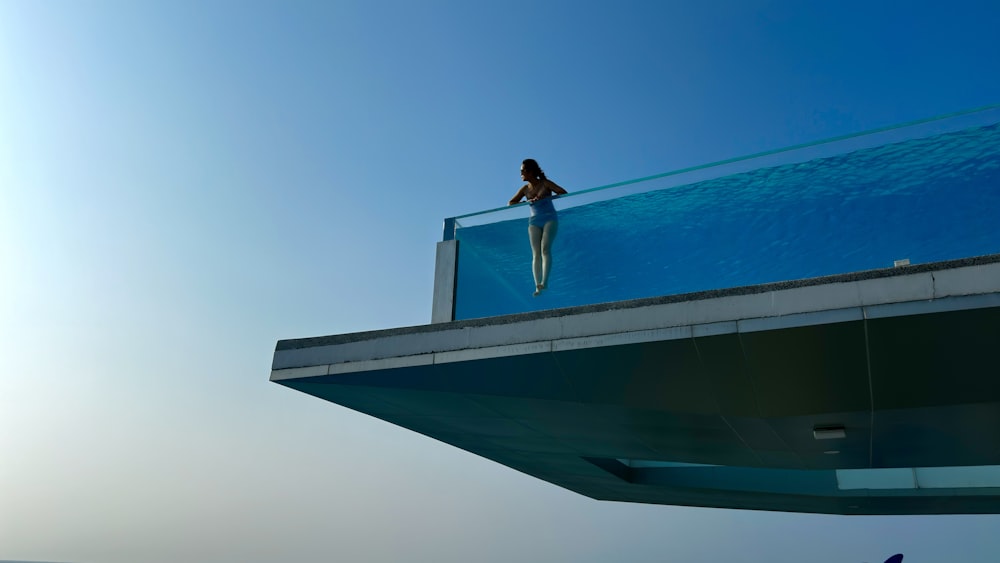 a woman standing on top of a balcony next to the ocean
