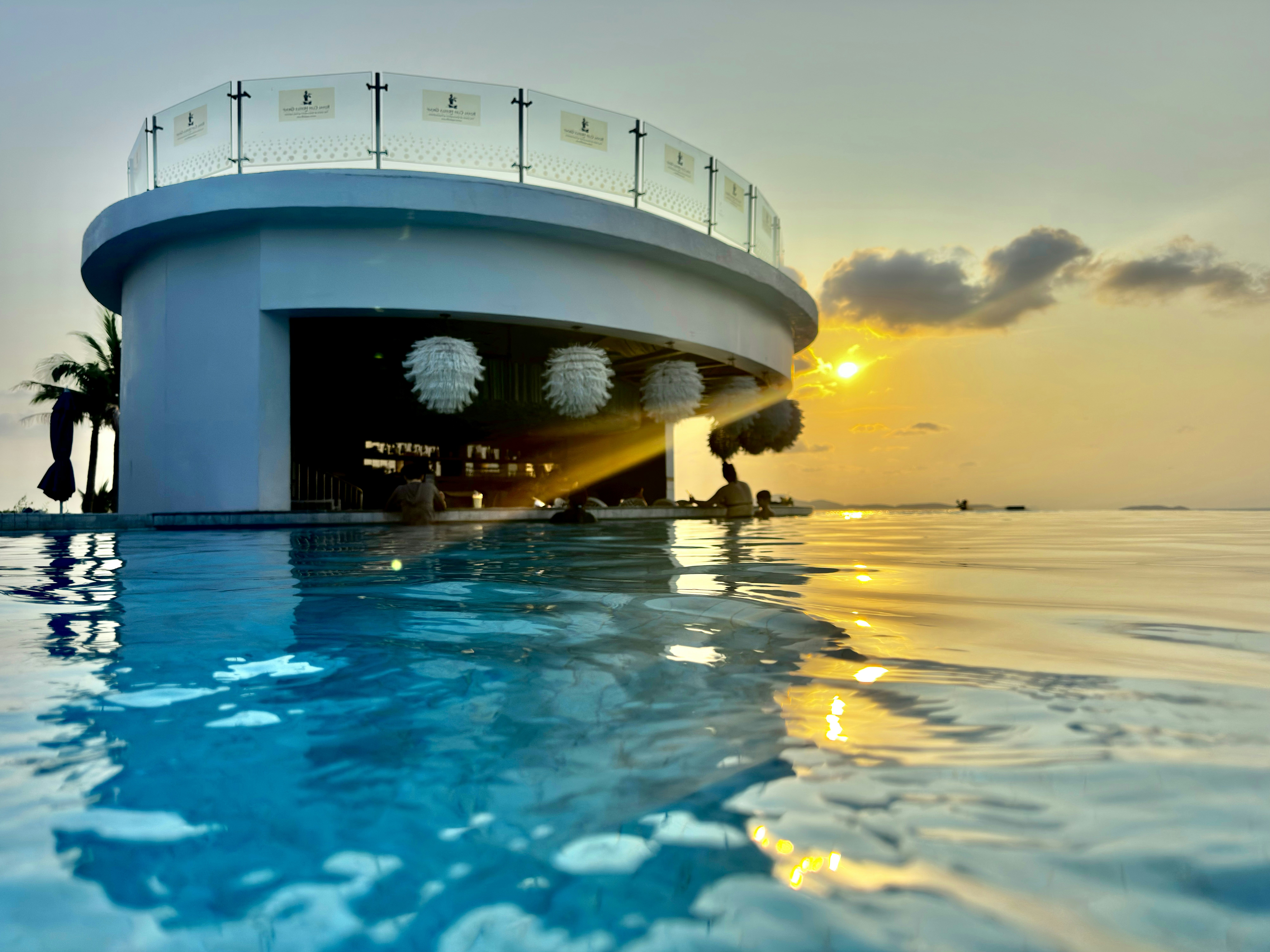 a large swimming pool with a sun setting in the background