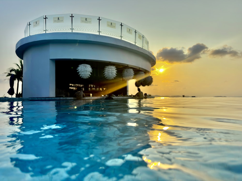 a large swimming pool with a sun setting in the background