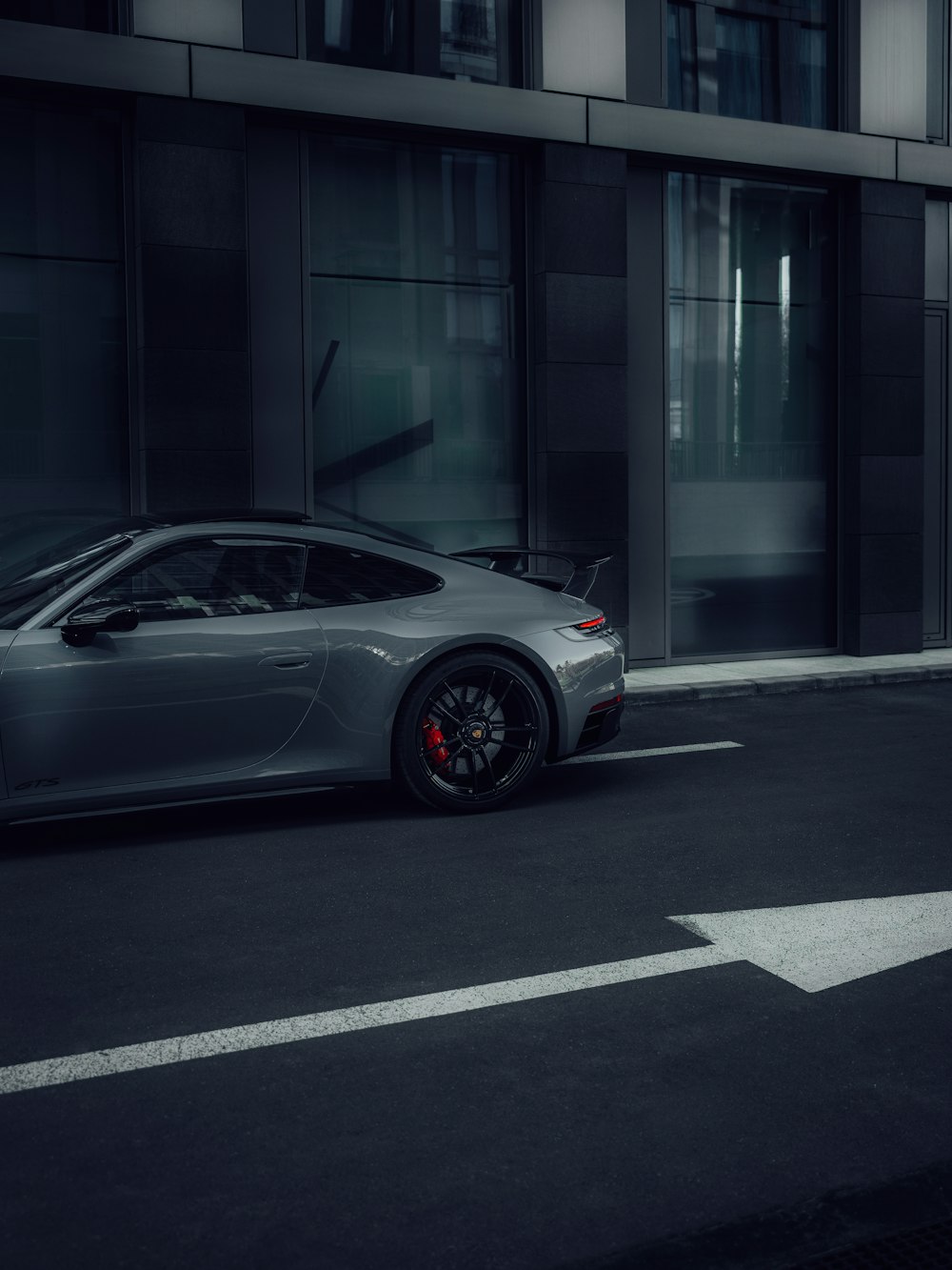 a grey sports car parked in front of a building
