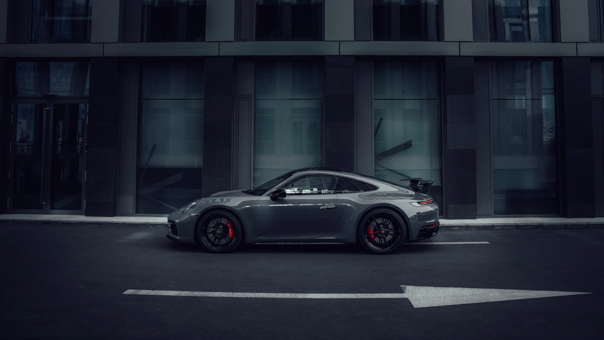 a grey sports car parked in front of a building