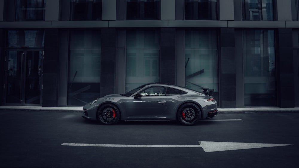 a grey sports car parked in front of a building