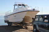 a white boat is being towed by a truck