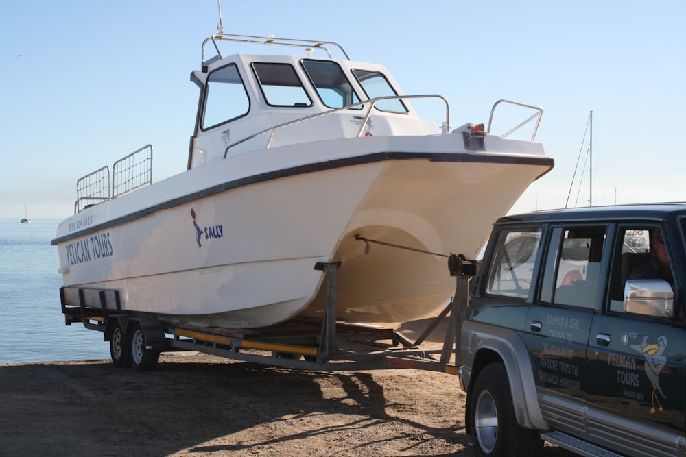 a white boat is being towed by a truck