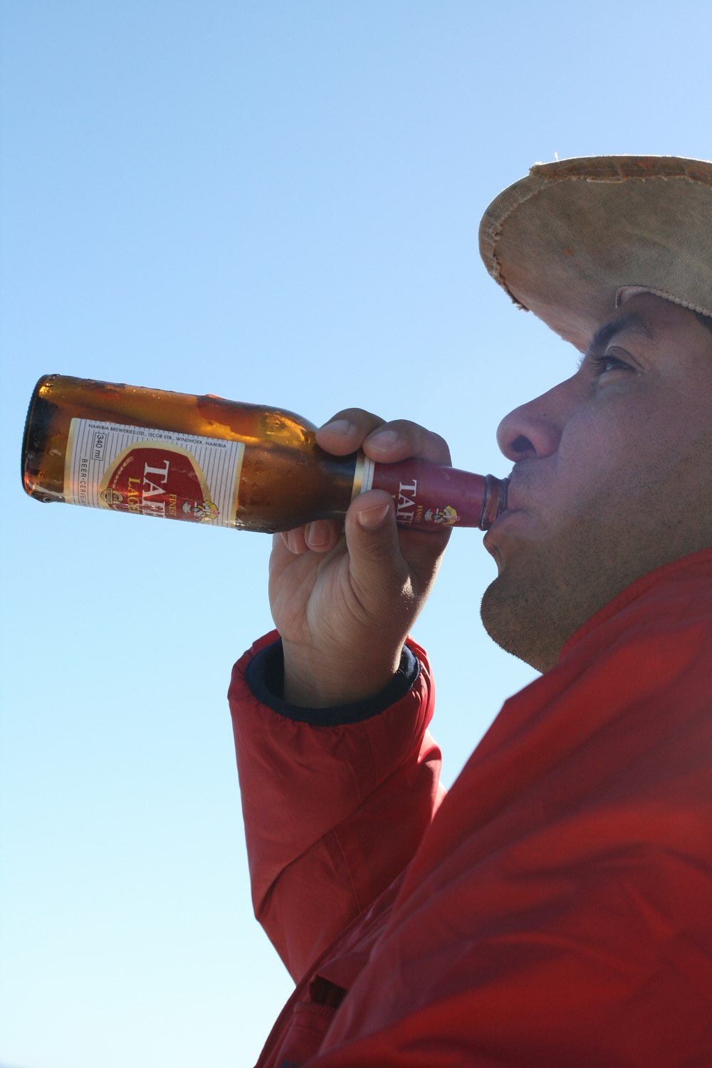 Un hombre con una chaqueta roja bebiendo de una botella