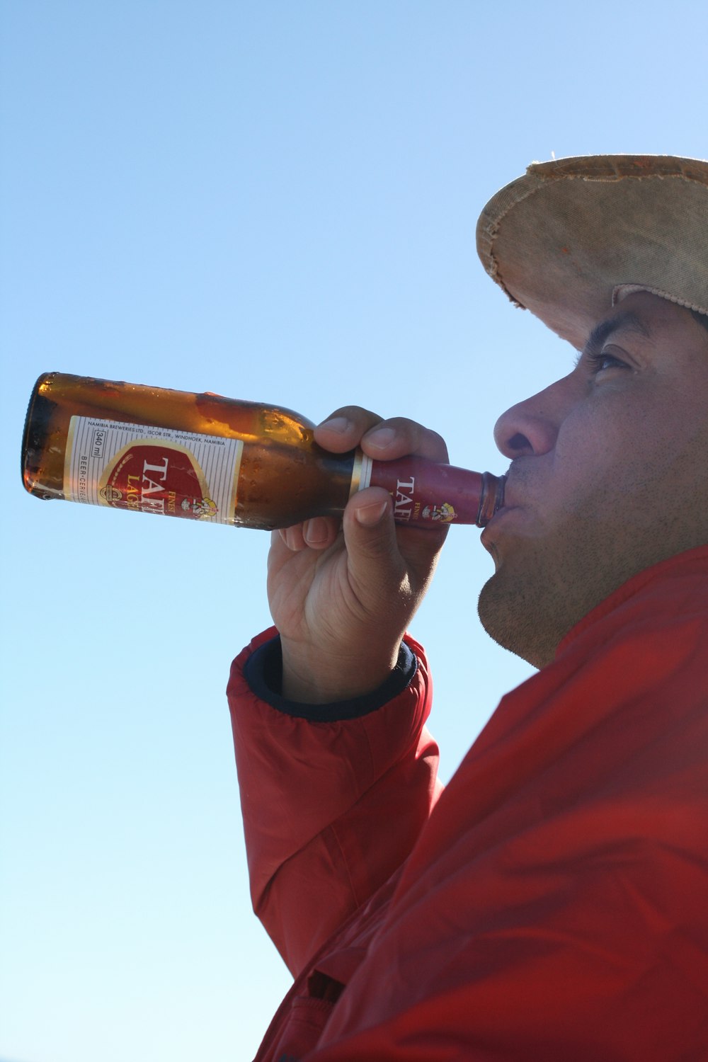 a man in a red jacket drinking from a bottle