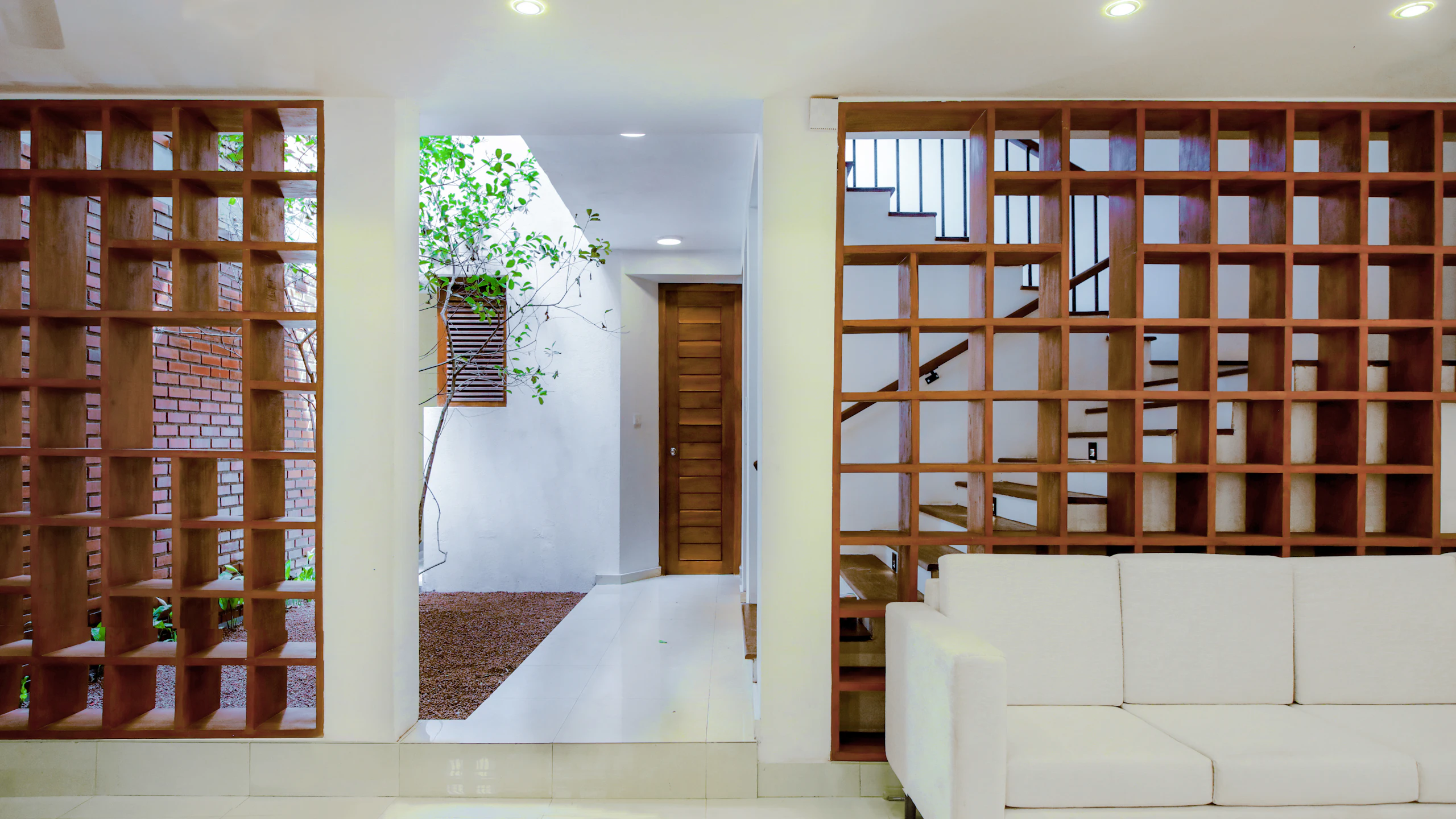 A living room framed by a brick jaali shelf wall