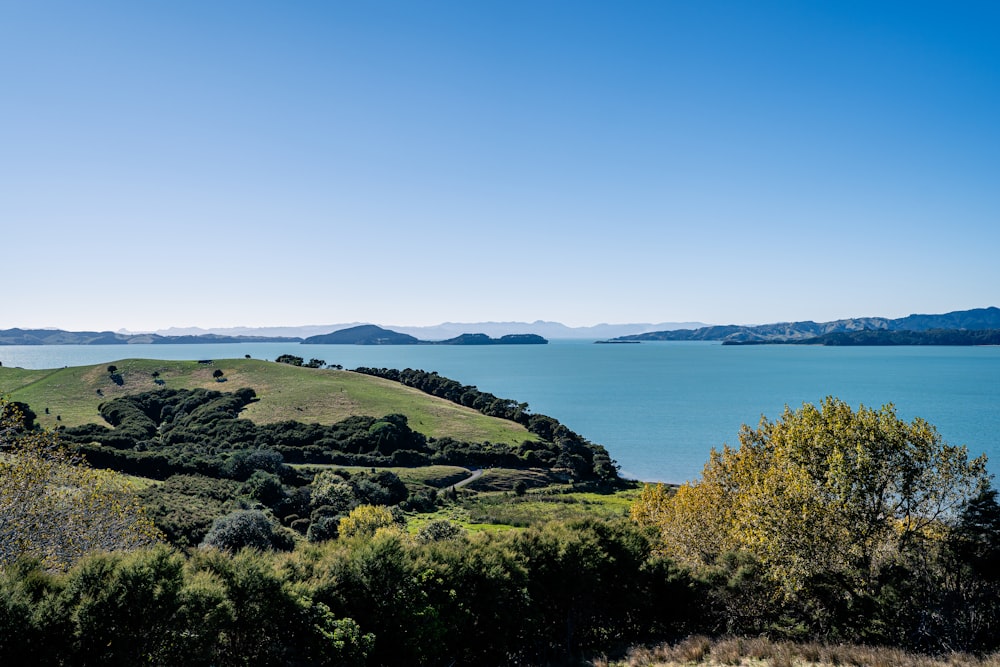 a large body of water sitting next to a lush green hillside