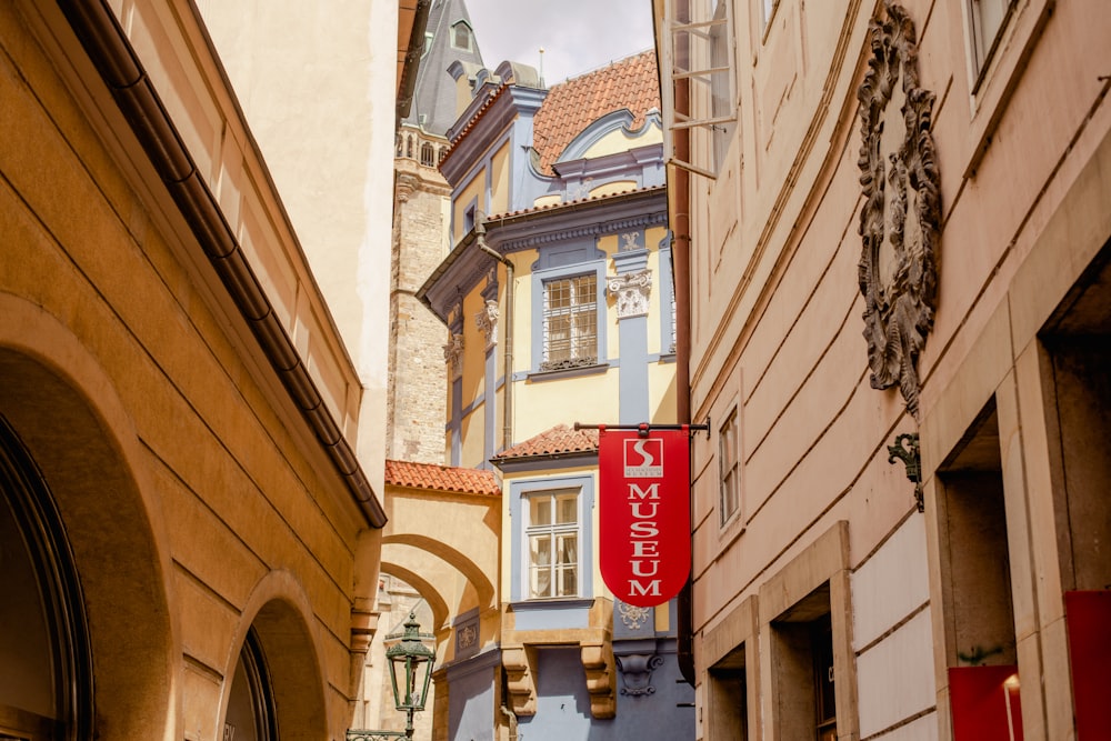 a narrow city street with buildings and a red sign